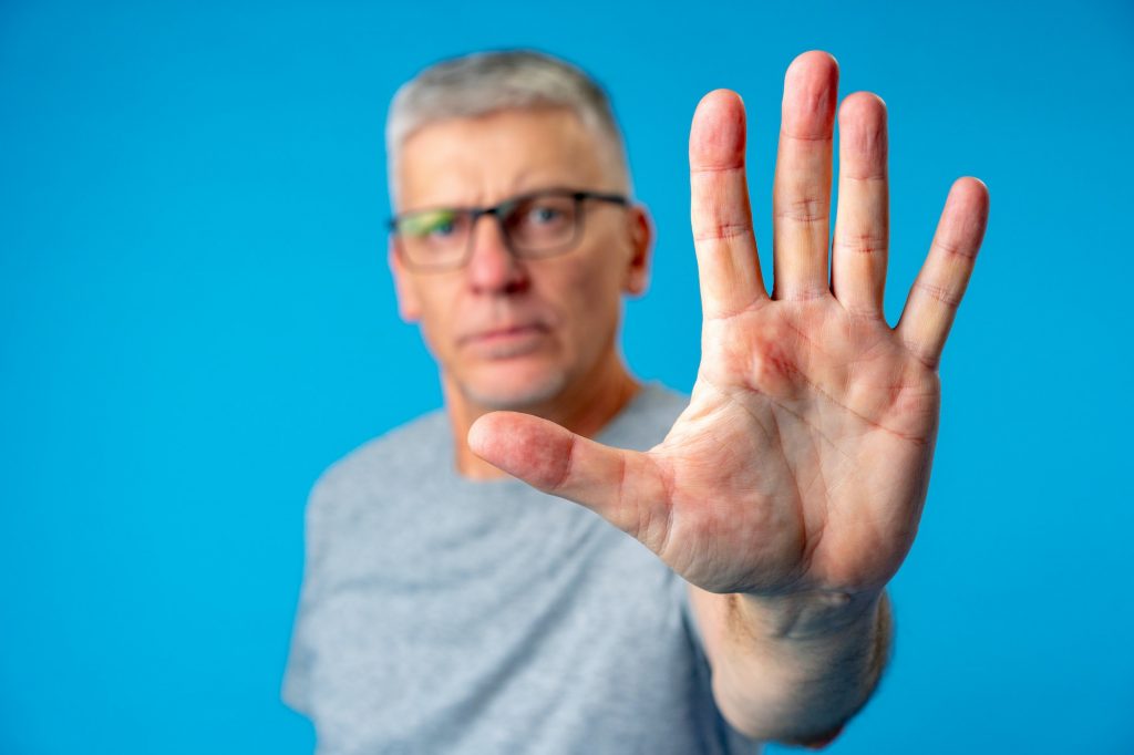 Middle age senior man over blue background doing stop sign with palm of the hand