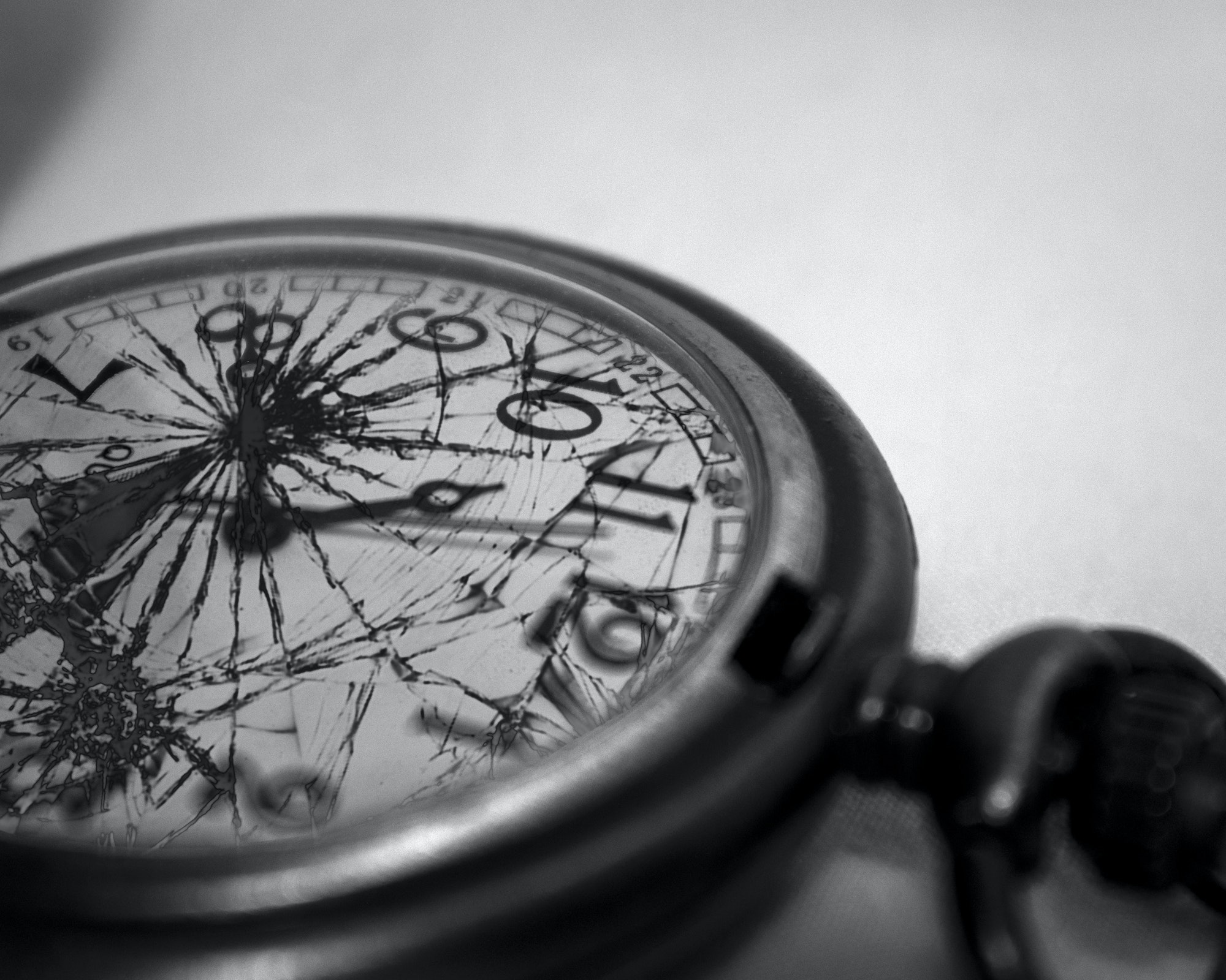 Closeup grayscale shot of an old watch with broken glass on it