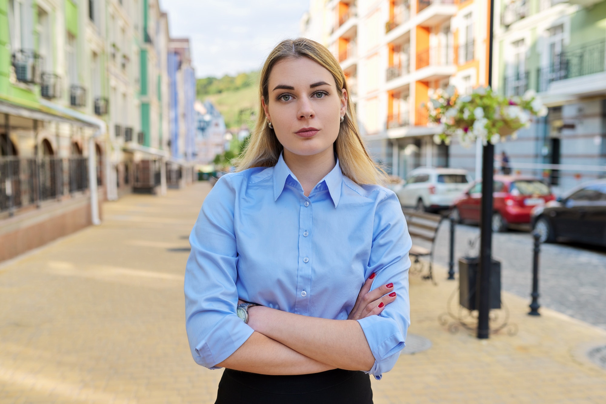 Outdoor portrait of young confident business woman with crossed arms