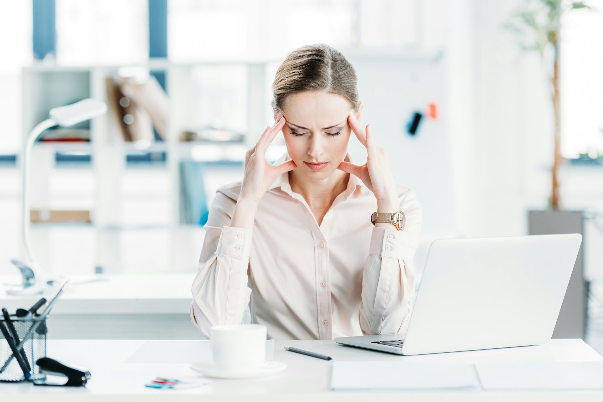 portrait of stressed businesswoman sitting at workplace in modern office