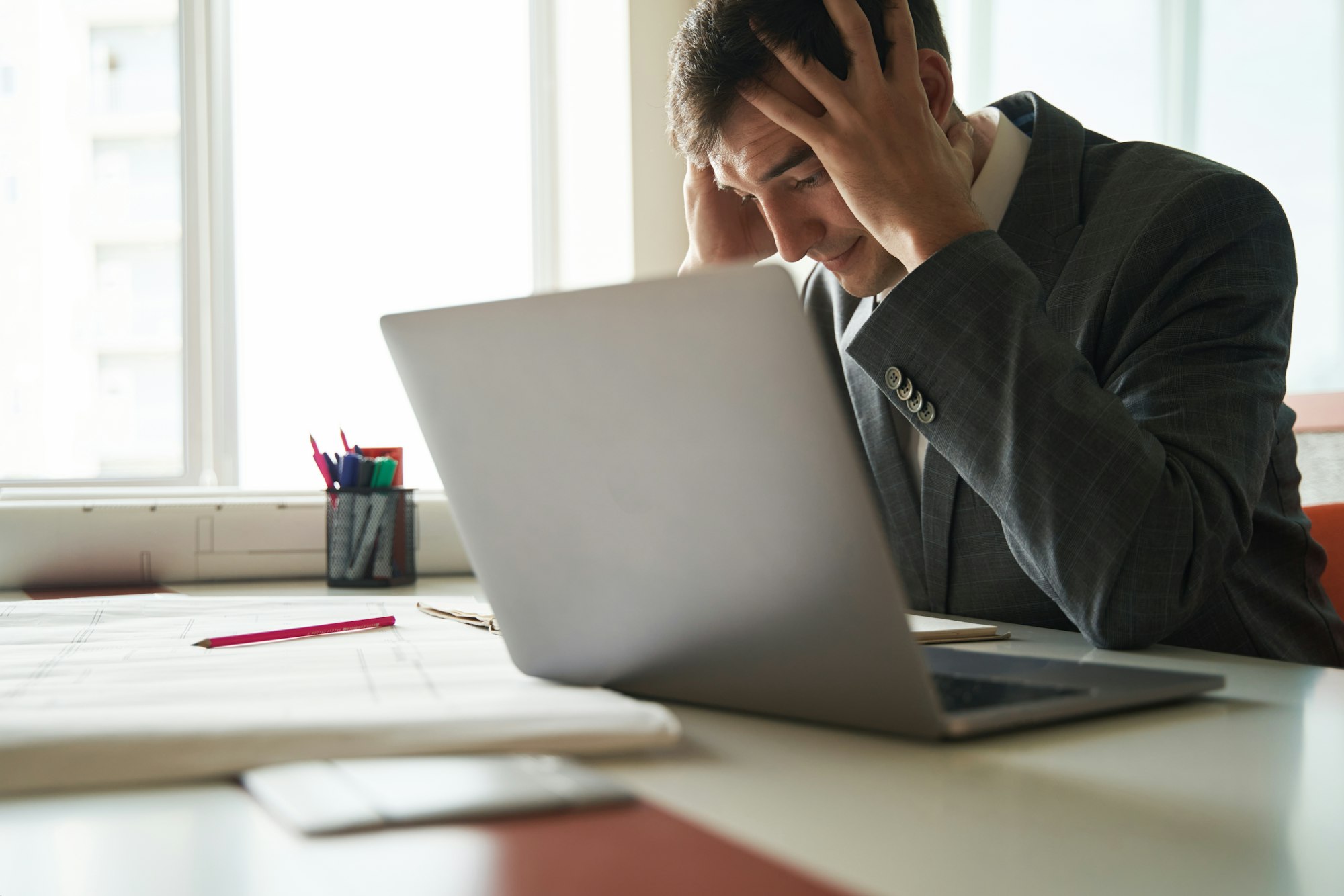 Stressed worker grabbing his head during work on laptop
