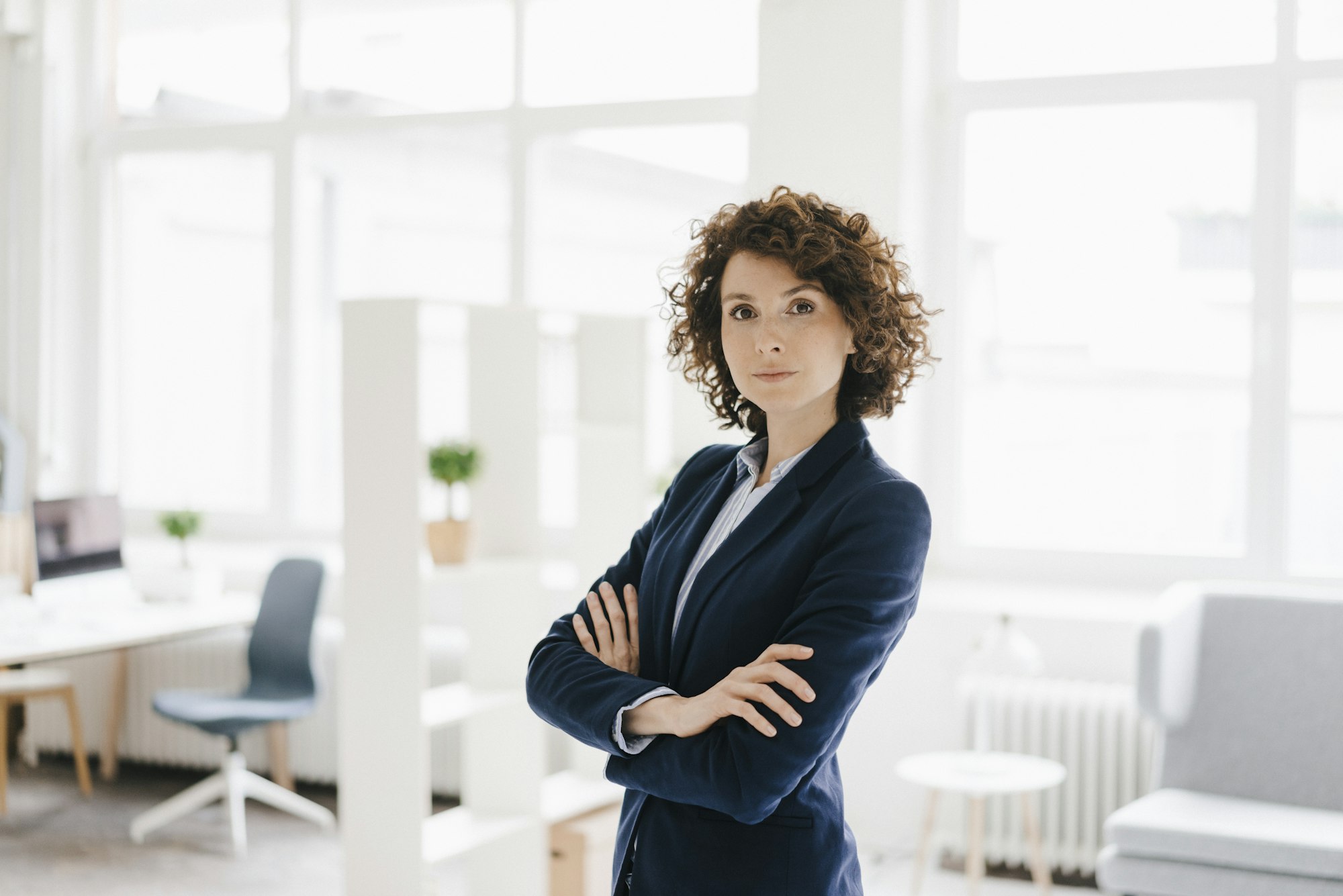 Businesswoman standing in her office with arms crossed