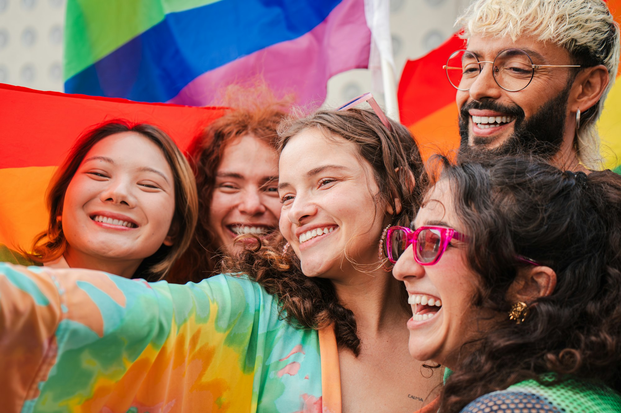Close up portrait of a group of LGBT poeple having fun celebrating the gay pride day with a rainbow
